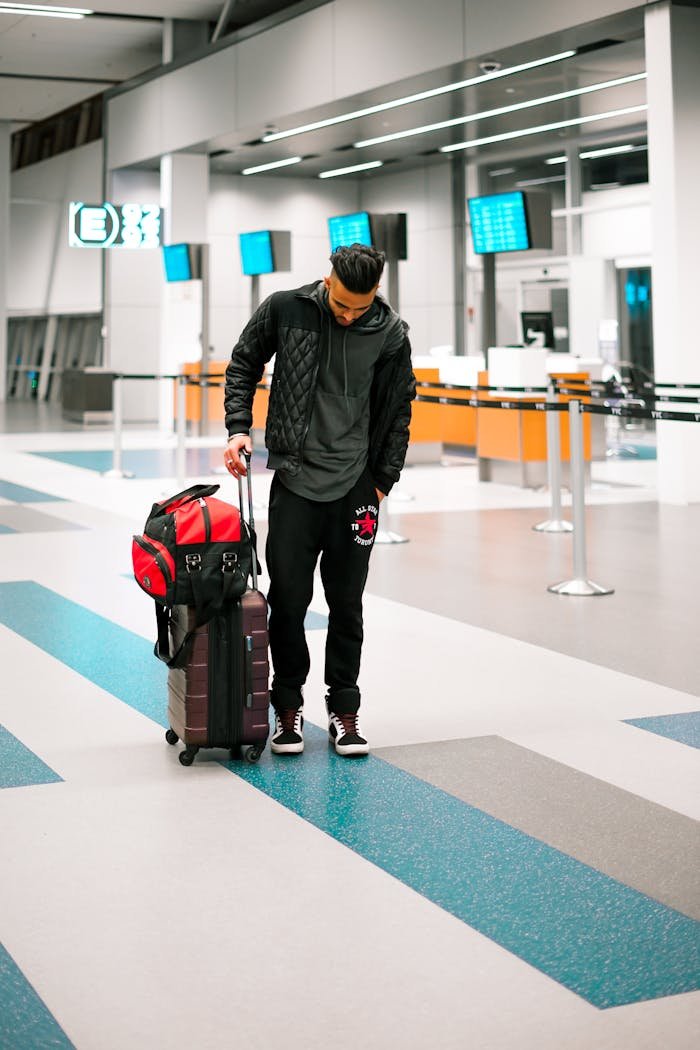Man standing with luggage in a modern airport terminal, ready for travel.